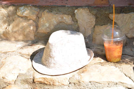 Orange smoothies, juice, cocktail of fresh fruit carrots orange. Hat on a background of stones in the city. concept travel vacation, diet, healthの写真素材