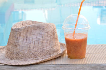 Orange smoothies, juice, cocktail of fresh fruit carrots orange. Hat on a background pool. concept travel vacation, diet, healthの写真素材