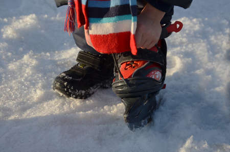 the boy dresses skates for hockey. enjoys winter. Winter sports. Kids ice skating in winter park rink. Children ice skate on Christmas fair.の写真素材