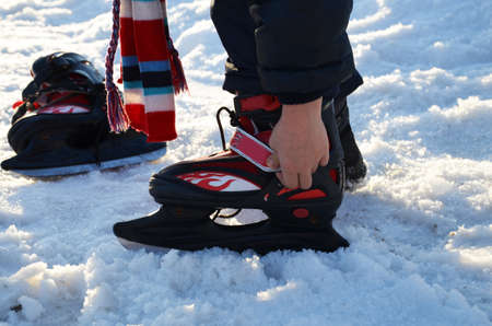 the boy dresses skates for hockey. enjoys winter. Winter sports. Kids ice skating in winter park rink. Children ice skate on Christmas fair.の写真素材