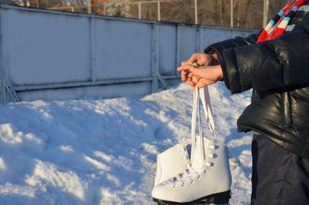cute little boy wearing warm winter clothes going ice skating. skates for figure skating. skating rink on the street. enjoys winter. Winter sportsの写真素材