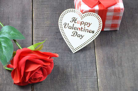 Gift or present box with red bow ribbon and glitter heart on wooden table for Valentines dayの写真素材