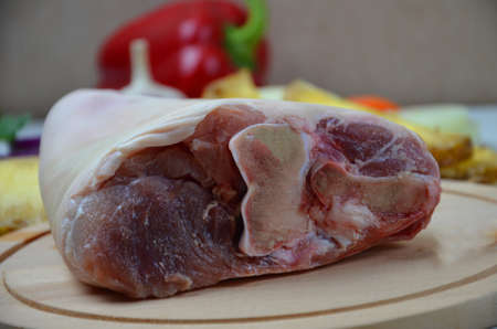 Raw pork leg on wooden cutting board ready for cooking with vegetablesの写真素材
