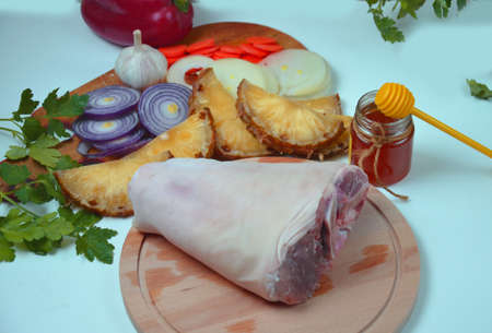 Raw pork knuckle with onion, carrot, garlic, cloves, honey, soy sauce on wood.の写真素材