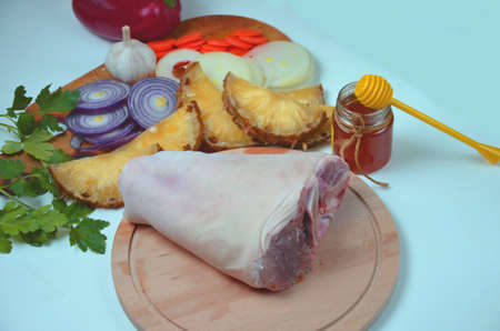 Raw pork knuckle with onion, carrot, garlic, cloves, honey, soy sauce on wood.の写真素材