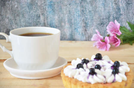 Cup of coffee and sweet cakes with berries on wooden tableの写真素材