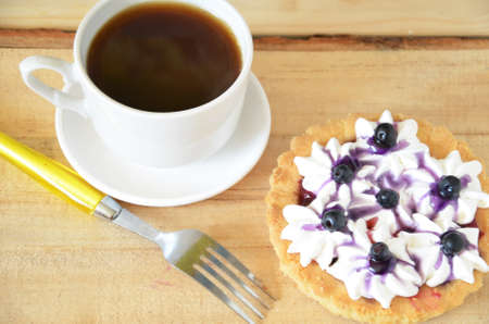 Cup of coffee and sweet cakes with berries on wooden tableの写真素材