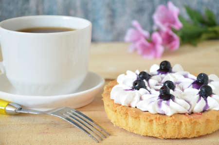 Cup of coffee and sweet cakes with berries on wooden tableの写真素材