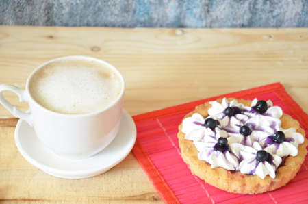 Cup of coffee and sweet cakes with berries on wooden tableの写真素材