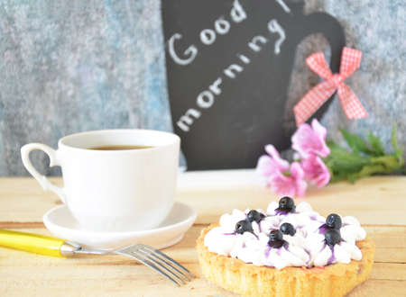 Cup of coffee with three cakes on a black background and a "good morning" textの写真素材