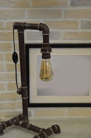 old retro vintage table lamp on brick wall background and photo framesの写真素材