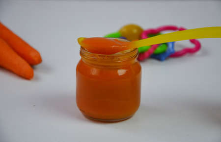 baby mashed with spoon in glass jar on white backgroundの写真素材