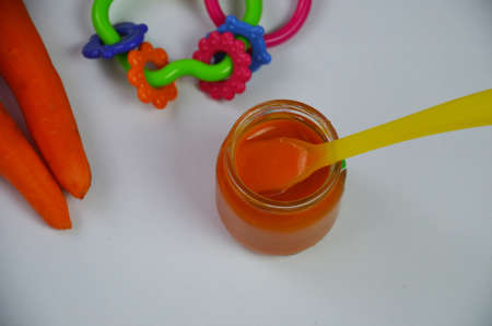 baby mashed with spoon in glass jar on white backgroundの写真素材