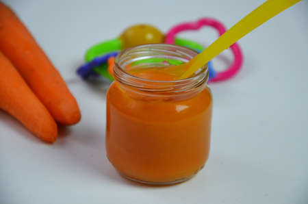 baby mashed with spoon in glass jar on white backgroundの写真素材