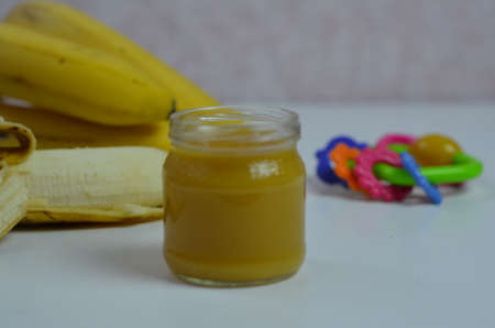 Baby food, banana mashed puree and bananas on a white backgroundの写真素材