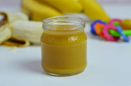 Baby food, banana mashed puree and bananas on a white backgroundの写真素材