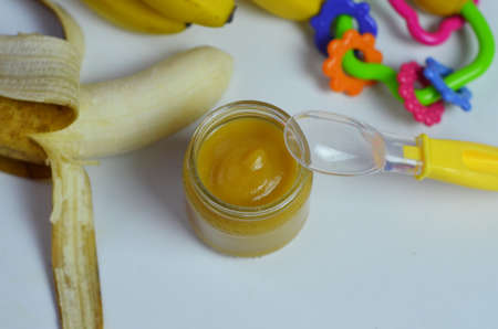 Baby food, banana mashed puree and bananas on a white backgroundの写真素材