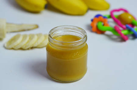 Baby food, banana mashed puree and bananas on a white backgroundの写真素材