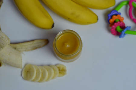 Baby food, banana mashed puree and bananas on a white backgroundの写真素材