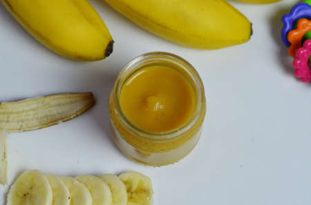 Baby food, banana mashed puree and bananas on a white backgroundの写真素材
