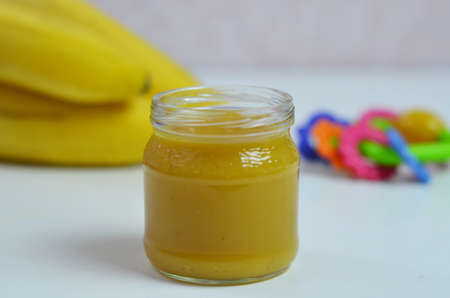 Baby food, banana mashed puree and bananas on a white backgroundの写真素材