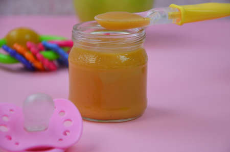 Fresh, organic pureed fruits for baby. mashed green apple. homemade, organic, healthy baby foods. on pink background. baby spoonの写真素材