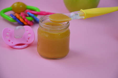 Fresh, organic pureed fruits for baby. mashed green apple. homemade, organic, healthy baby foods. on pink background. baby spoonの写真素材