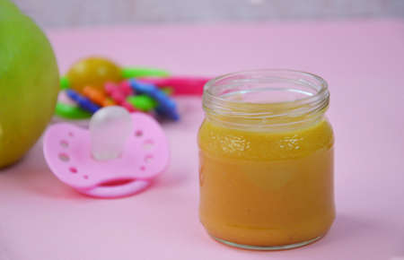 Fresh, organic pureed fruits for baby. mashed green apple. homemade, organic, healthy baby foods. on pink background. baby spoonの写真素材