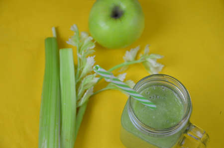 Detox green smoothie juice with celery, cucumber, dill and apple on a yellow background. Healthy food.の写真素材