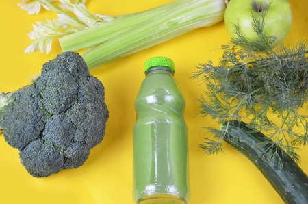 Detox green smoothie juice with celery, cucumber, dill and apple on a yellow background. Healthy food.の写真素材