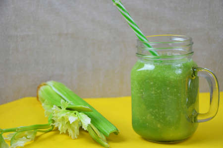 Detox green smoothie juice with celery, cucumber, dill and apple on a yellow background. Healthy food.の写真素材