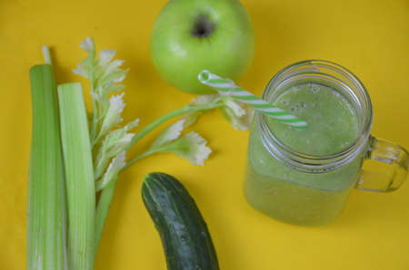 Detox green smoothie juice with celery, cucumber, dill and apple on a yellow background. Healthy food.の写真素材