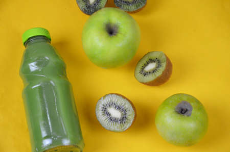 Kiwi and green Apple Fresh Juice in glass bottle on yellow background. Health diet drinkの写真素材