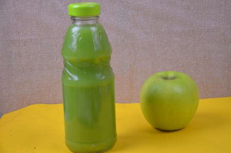 Kiwi and green Apple Fresh Juice in glass bottle on yellow background. Health diet drinkの写真素材
