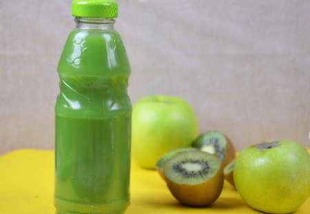 Kiwi and green Apple Fresh Juice in glass bottle on yellow background. Health diet drinkの写真素材