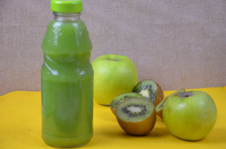Kiwi and green Apple Fresh Juice in glass bottle on yellow background. Health diet drinkの写真素材