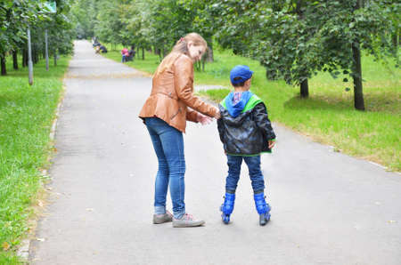 A mother teaching her son skating on a rollerblade in the parkの写真素材