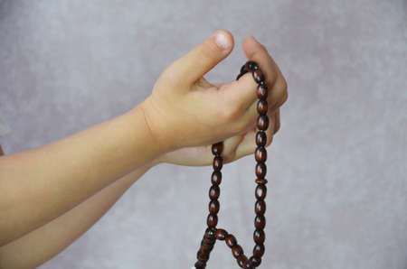 Young muslim boy prayer during holy month of Ramadhan with rosary beads in hand.の写真素材