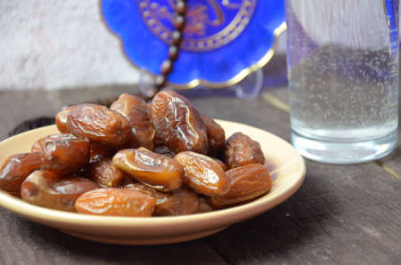 A glass of drinking water and date fruits - a food that is consumed before breaking fast during holy month of Ramadan.の写真素材