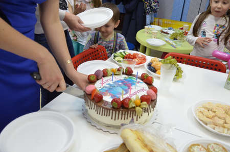Hand cut the birthday cake with knifeBirthday cake with the inscription. A table full of sweets and snacksの写真素材