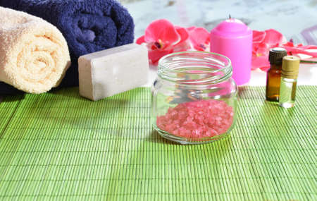 spa pink sea solt very close up. Two towels, soap, candle, aroma oil, pink flowerの写真素材