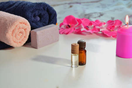 Spa cosmetic products concept, spa background with a space for a text, flat lay, view from above. Two towels, soap, candle, aroma oil, pink flowerの写真素材