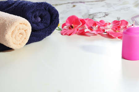 Spa cosmetic products concept, spa background with a space for a text, flat lay, view from above. Two towels, soap, candle, aroma oil, pink flowerの写真素材