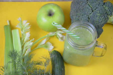 Detox healthy green smoothie in mason jar with ingredients: spinach, celery, cucumber, lettuce, ginger, fennel, lime and broccoli on a tray on white wooden background. Clean eating concept. Top view.の写真素材