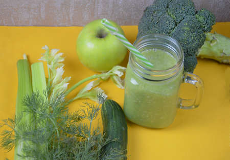 Detox healthy green smoothie in mason jar with ingredients: spinach, celery, cucumber, lettuce, ginger, fennel, lime and broccoli on a tray on white wooden background. Clean eating concept. Top view.の写真素材