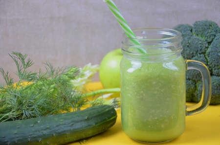 Detox healthy green smoothie in mason jar with ingredients: spinach, celery, cucumber, lettuce, ginger, fennel, lime and broccoli on a tray on white wooden background. Clean eating concept. Top view.の写真素材