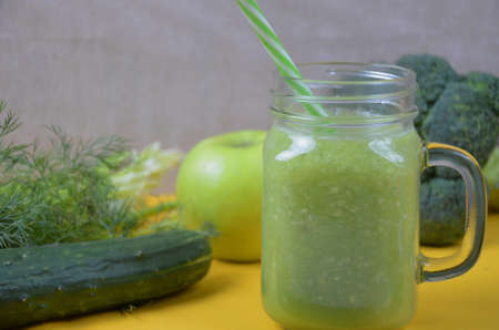 Detox healthy green smoothie in mason jar with ingredients: spinach, celery, cucumber, lettuce, ginger, fennel, lime and broccoli on a tray on white wooden background. Clean eating concept. Top view.の写真素材