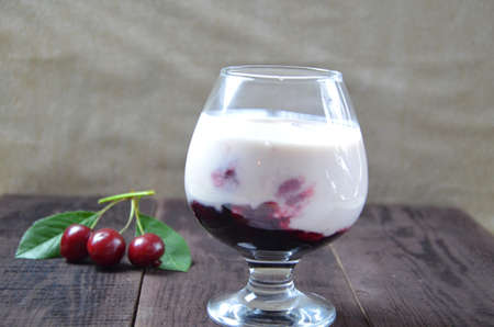 Cherry yogurt dessert or pudding and ripe cherry on a wooden table. Summer dessert.の写真素材
