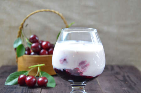 Cherry yogurt dessert or pudding and ripe cherry on a wooden table. Summer dessert.の写真素材