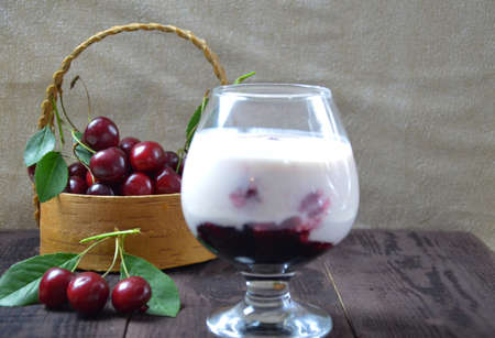 Cherry yogurt dessert or pudding and ripe cherry on a wooden table. Summer dessert.の写真素材
